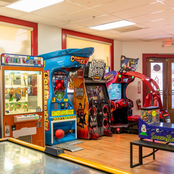 A vibrant arcade room at Corsaro's Family Pizza, featuring various games like Guitar Hero and a prize locker.