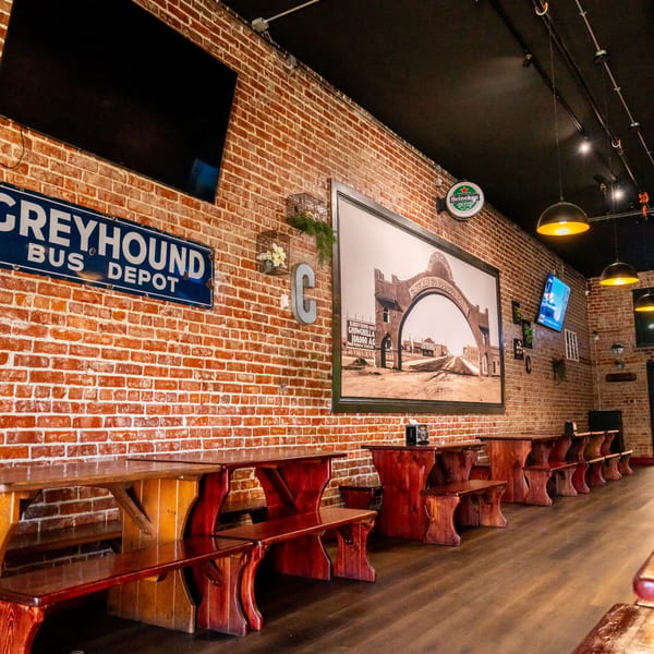 Interior of Corsaro's Family Pizza with brick walls, wooden tables, and historical decor.