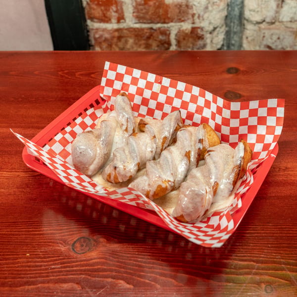 Corsaro's Family Pizza's cinnamon knots, drizzled with white icing, in a red basket with checkered paper.