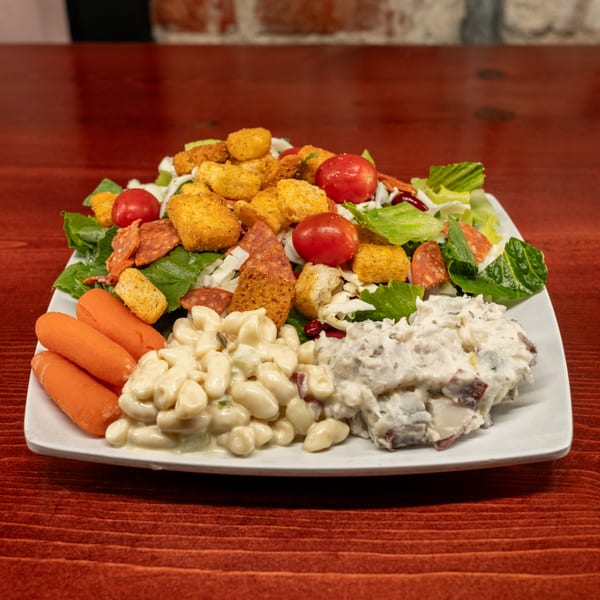 A Corsaro's Family Pizza salad with pepperoni, croutons, tomatoes, carrots, macaroni salad, and potato salad.